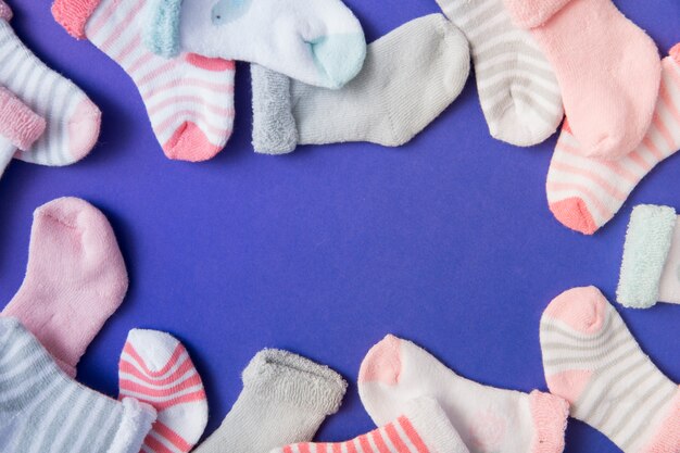 Border made with many baby's socks on blue background