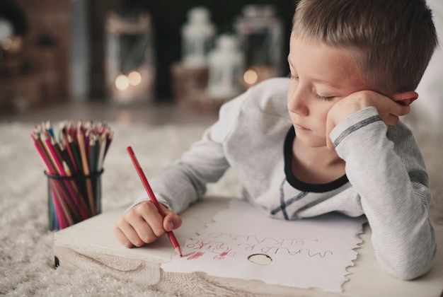 Free photo bored boy drawing on floor