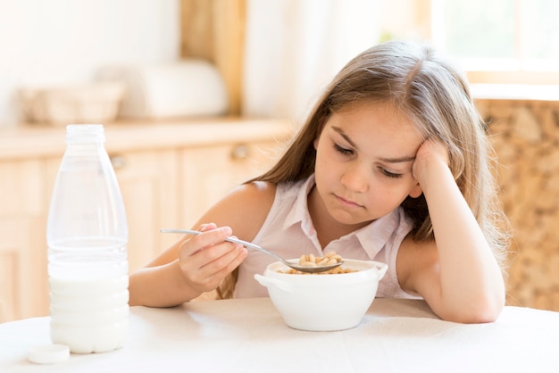 Free photo bored young girl eating cereals for breakfast