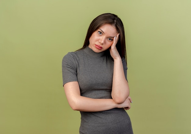 Bored young pretty woman putting hand on head looking at camera isolated on olive green background with copy space