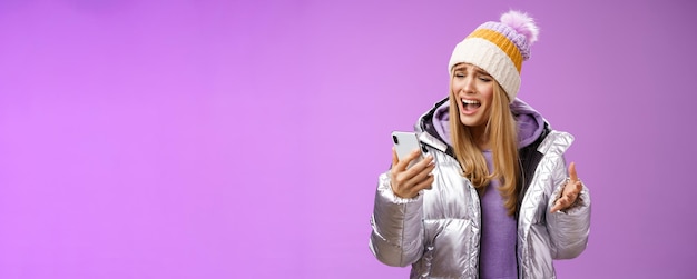 Free Photo bothered complaining dissatisfied cute blond girl yelling stupid smartphone standing unhappy recording audio message whining yelling mobile phone upset standing purple background