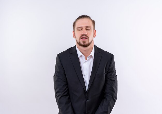 Bothered handsome business man wearing suit with closed eyes standing over white background