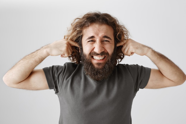 Free photo bothered middle-eastern man shut ears and grimacing from loud disturbing noise