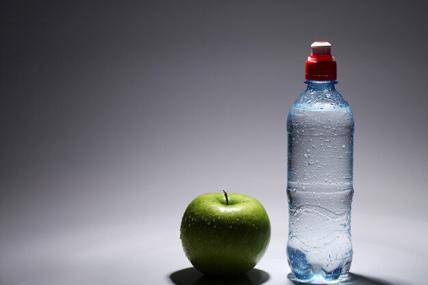 Bottle of fresh cold water and green apple