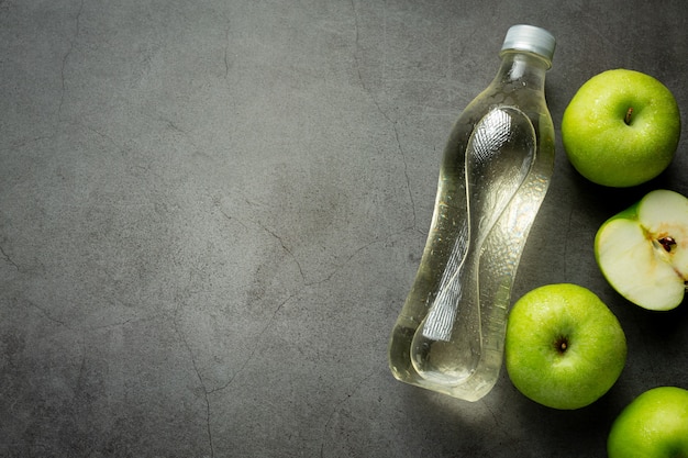 A bottle of green apple healthy juice put next to fresh green apples