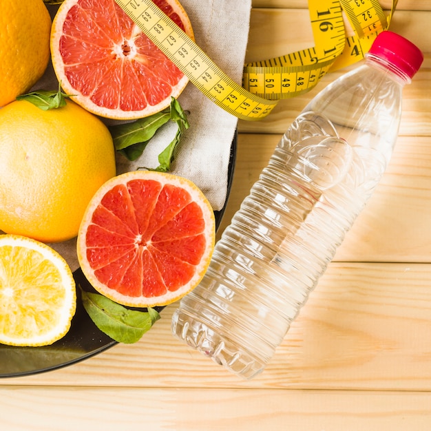 Free photo bottle; measuring tape and citrus fruits on plate