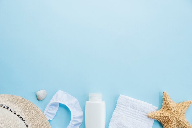 Bottle near towel with starfish and hat