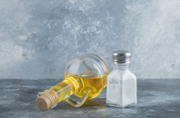 Free photo bottle of oil and salt on grey background