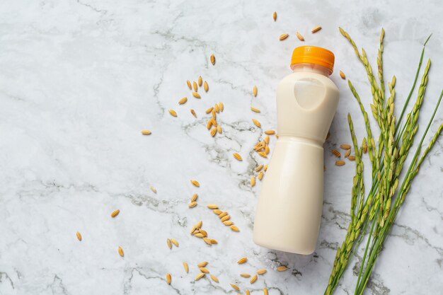 Bottle of rice milk with rice plant and rice seed put on white marble floor