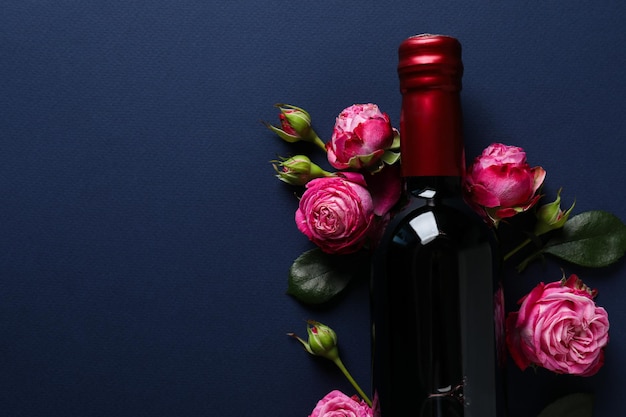 Free photo a bottle of wine on a dark background with flowers and a snack