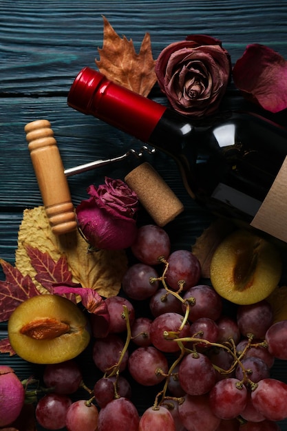 Free photo a bottle of wine on a dark background with flowers and a snack