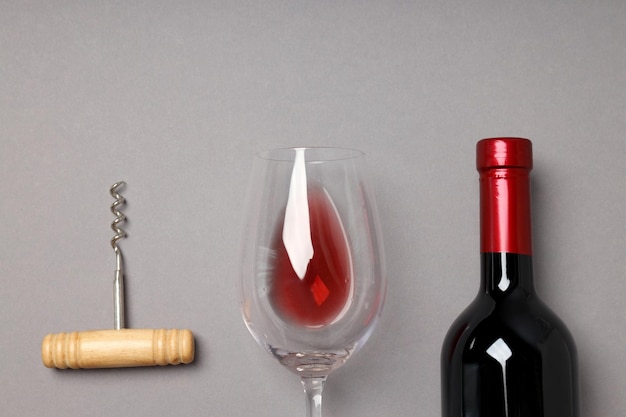 Free photo a bottle of wine a glass and a corkscrew on a gray background