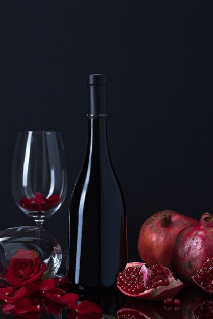 Bottle of wine with pomegranates, goblets and rose petals