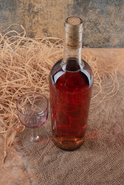 Free photo bottle of wine with wineglass on burlap