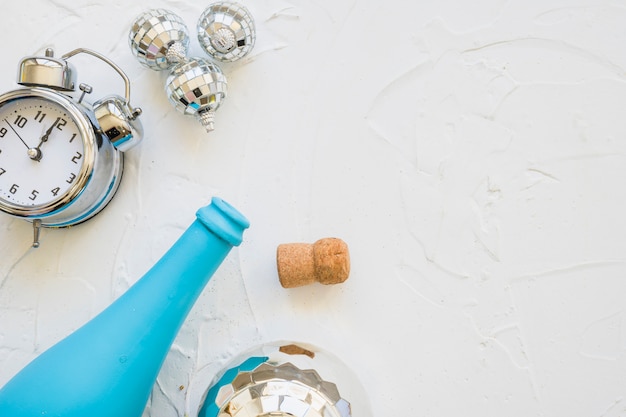 Bottle with clock and baubles on white table