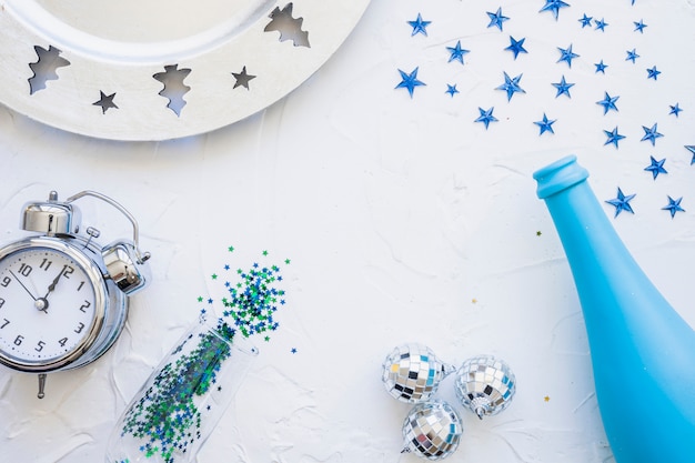 Bottle with clock and spangles on table