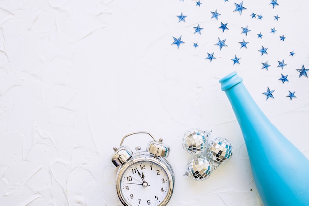 Free photo bottle with clock and spangles on white table