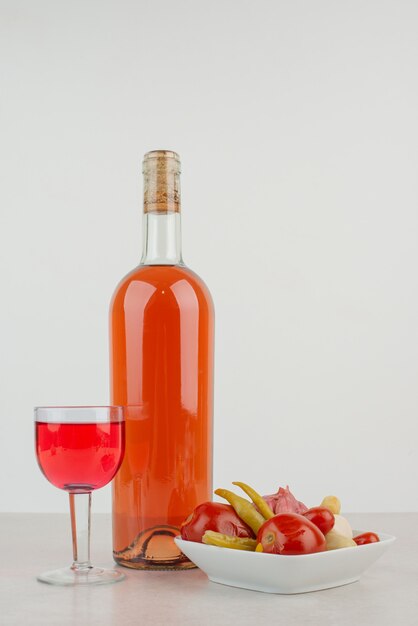 Bottle with glass of lemonade and plate of dumplings .