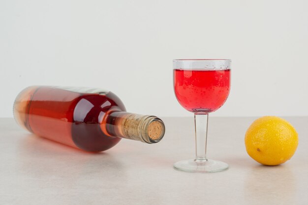 Bottle with glass of lemonade with lemon .