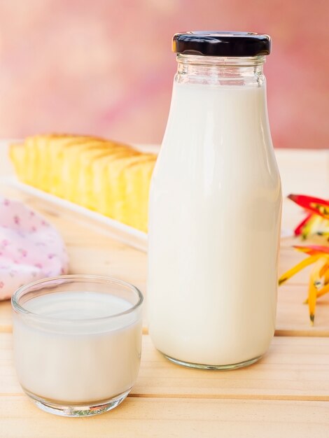 Bottle with glass of milk and butter cake on white wooden table.