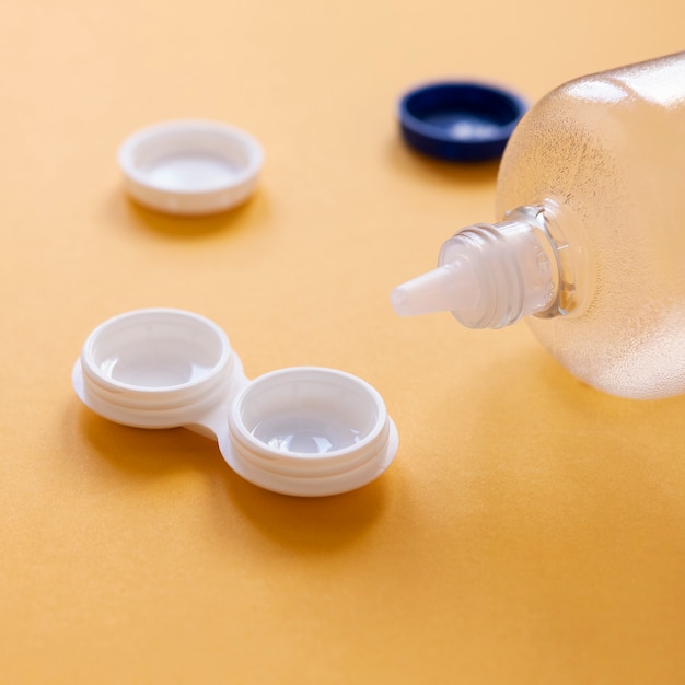 Free photo bottle with lens solution and lens box  on orange background