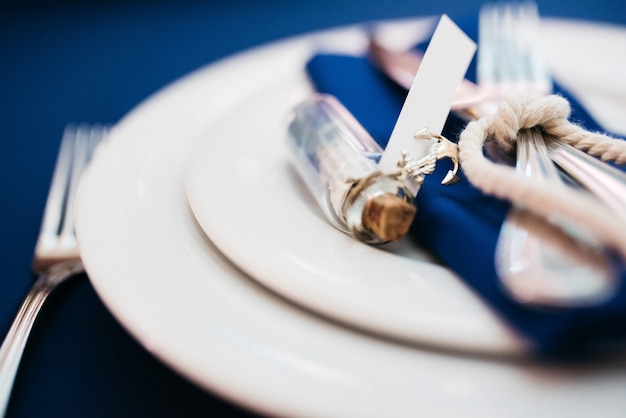 Bottle with a letter lies on the blue serviette on dinner table