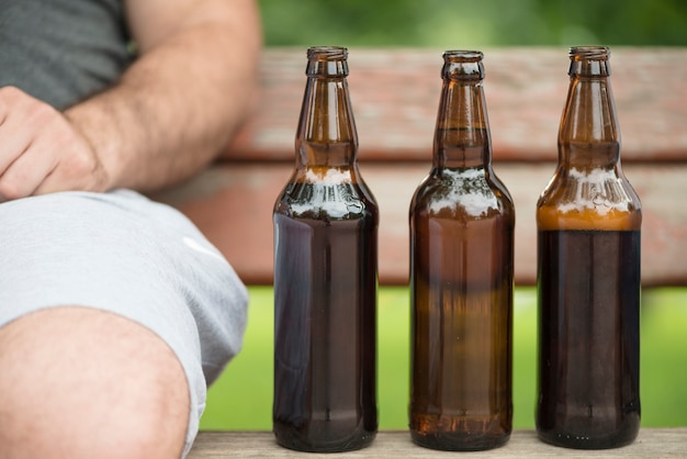 Free photo bottles of beer on bench near crop man