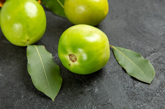 Bottom close view green tomatoes bay leaves on dark background