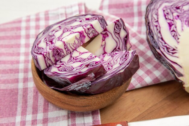 Bottom close view red cabbage in bowls purple white checkered kitchen towel on cutting board on grey table