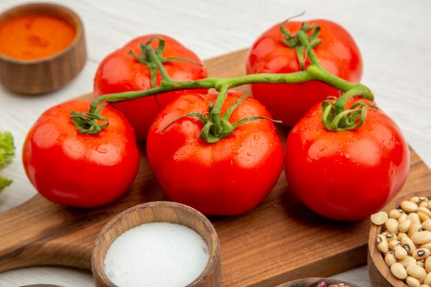 Bottom close view tomato branch on cutting board salt turmeric on grey table