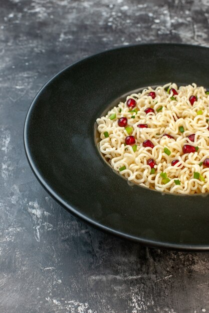 Bottom half view asian ramen noodles on black round plate on dark table