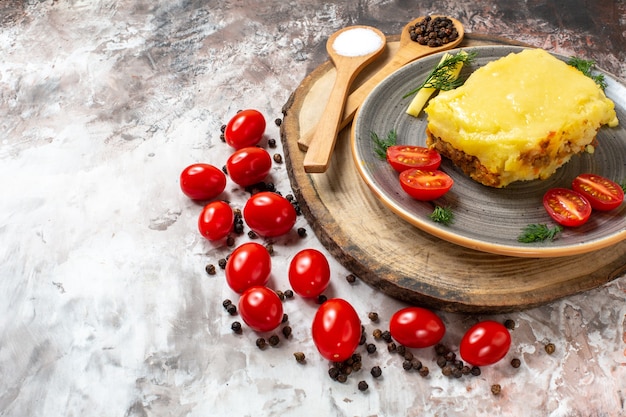 Free photo bottom half view cheesy bread tomatoes on plate wooden spoons on rustic serving board cherry tomatoes on table copy place