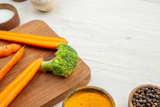 Bottom half view chopped carrots and broccoli on cutting board mushrooms different spices in bowls on table free place