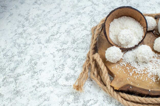 Bottom half view coconut powder bowl coconut balls on wood board on grey background