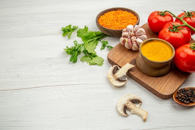 Bottom half view fresh tomato branch garlic turmeric bowl on chopping board mushrooms lentile bowl on grey table free space