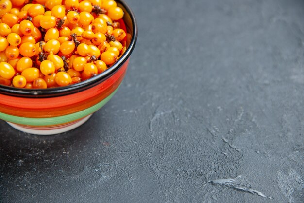 Bottom half view sea buckthorn in bowl on dark surface free space