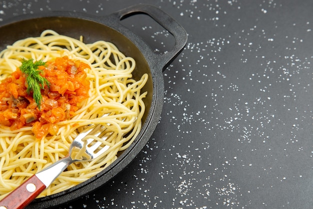 Bottom half view spaghetti with sauce in frying pan on black table