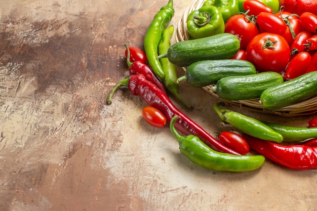 Bottom half view vegetables in a wicker basket surrounded by peppers and cherry tomatoes on amber background