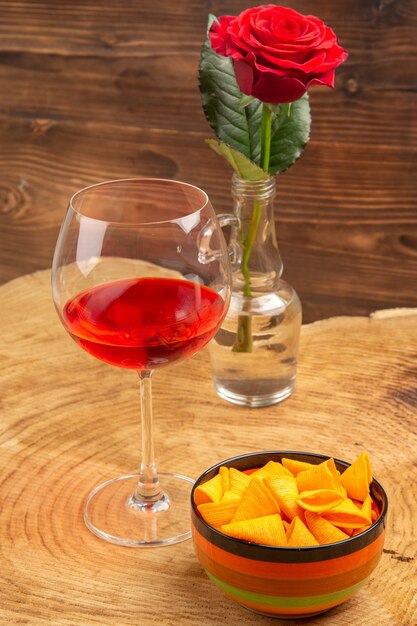 Bottom view balloon wine glass chips in bowl red rose on brown surface