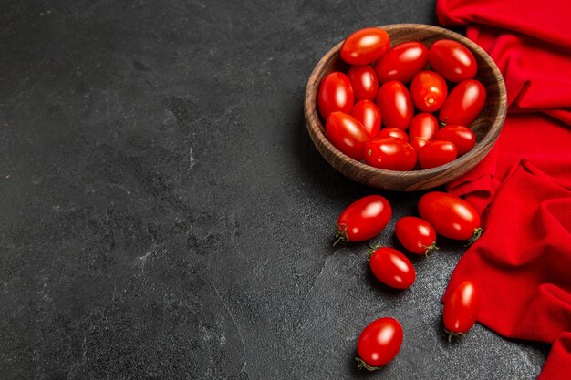 Bottom view bowl with cherry tomatoes red towel on dark background