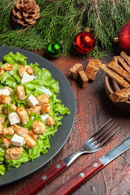 Bottom view caesar salad on oval plate fork knife bowl with dried crust on dark red table