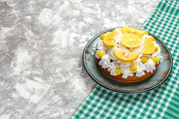 Free photo bottom view cake with white pastry cream and lemon slices on round plate on green and white checkered table