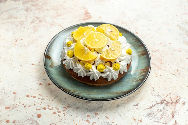 Free photo bottom view cake with white pastry cream and lemon slices on round plate on light grey table