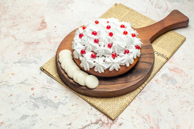 Bottom view cake with white pastry cream and white chocolate on cutting board on newspaper on light grey table