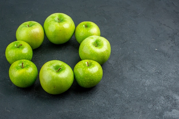 Bottom view circle row green apples on dark surface with free space