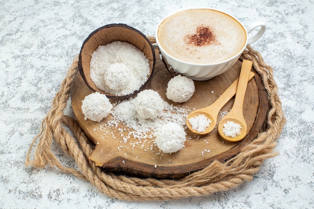 Bottom view cup of cappuccino bowl with coconut powder wooden spoons on wood board on grey background