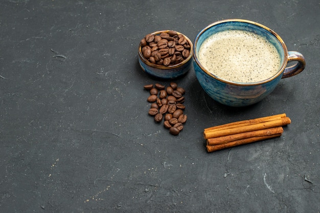 Free photo bottom view a cup of coffee bowl with coffee seeds cinnamon sticks on dark isolated background