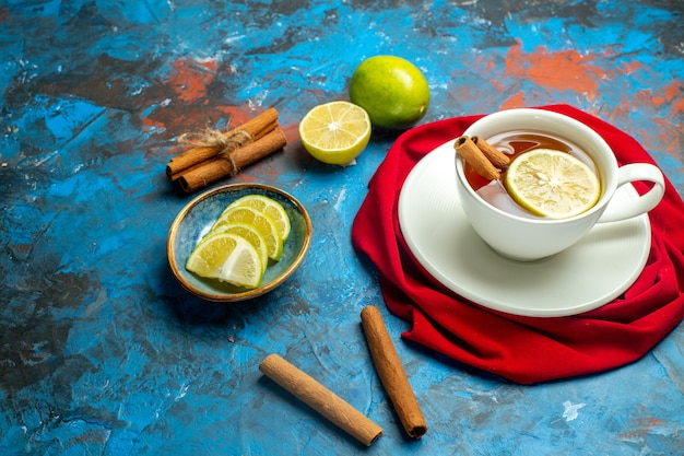 Bottom view cup of tea with lemon and cinnamon red shawl on blue red surface copy place