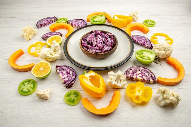 Bottom view cut red cabbages in bowl on round platter cut vegetables on white surface