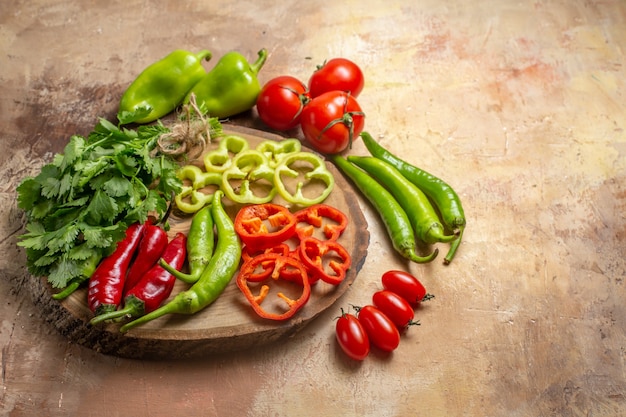 Bottom view different vegetables coriander hot peppers bell peppers cut into pieces on round tree wood board